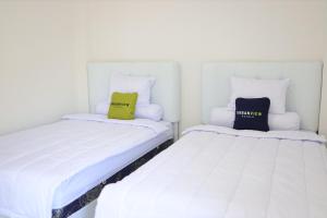 2 letti posti uno accanto all'altro in una stanza di Urbanview Hotel Eropa Maros Near Sultan Hasanuddin Airport a Maros