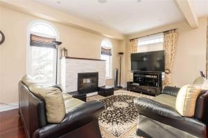 a living room with two leather couches and a fireplace at Jazzy Home Stay in Mississauga