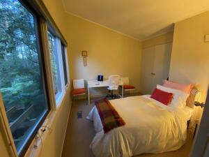 1 dormitorio con cama, escritorio y ventana en Sassafras Treehouse Private home in the Dandenong Ranges, Victoria, en Sassafras