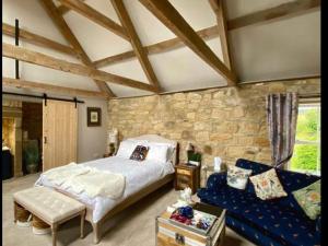 a bedroom with a bed and a stone wall at Bird In Bush Elsdon in Elsdon