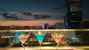 trois verres à vin assis sur un balcon avec vue sur les toits de la ville dans l'établissement Vinhomes West Point, à Hanoï
