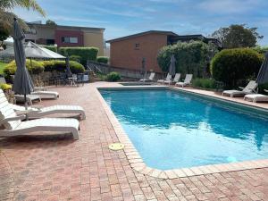 a swimming pool with lounge chairs and umbrellas next to at Pacific Heights in Merimbula