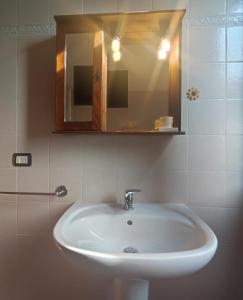 lavabo blanco en el baño con espejo en Casa del Sole en Riotorto