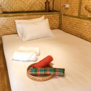 Ban Pha Saeng Lang的住宿－คุ้มกะลาหัวฟาร์มสเตย์ (Khumkalahua Farmstay)，一张带两条毛巾和一顶帽子的床