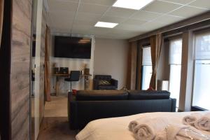 een kamer met een bed, een bank en een televisie bij Flat 40 by Malmedreams in Malmedy