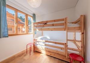 a bedroom with two bunk beds and two red chairs at Panoramapark Soleil E Apt 3 in Wengen