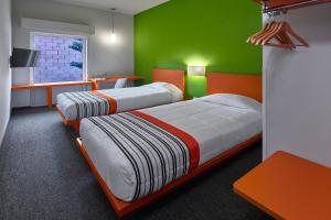 duas camas num quarto com verde e laranja em City Express Junior by Marriott Guadalajara Periferico Sur em Guadalajara