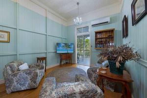 a living room with two chairs and a tv at A Charming Queenslander in Bundaberg