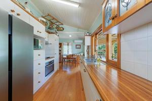 a large kitchen with white cabinets and a wooden floor at A Charming Queenslander in Bundaberg