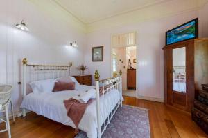 a bedroom with a white bed in a room at A Charming Queenslander in Bundaberg