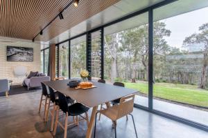 a dining room with a table and chairs and large windows at Boomerang House I Private Properties in Quindalup