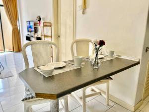 a table with chairs and a vase of flowers on it at Mahkota Prd Pahlawan Homestay 1Rom-4pax/free wi-fi in Malacca