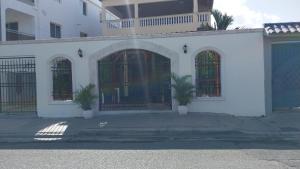 a white building with two palm trees in front of it at Residencial El Mirador in Boca Chica