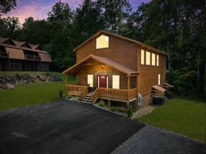eine Blockhütte mit einer roten Tür in einem Hof in der Unterkunft LUXURY 4BR Cabin in Gatlinburg with Views Hot Tub with Private Deck Game Room Most Popular Coffee Bar Perfect for Family Getaway Tennis Courts Infant Crib and Karaoke System in Gatlinburg