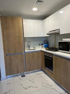 a kitchen with white cabinets and a sink and a refrigerator at Al Raha lofts 1 in Al Qurayyah