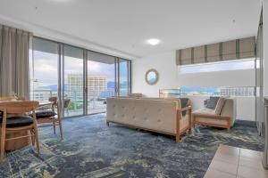 ein Wohnzimmer mit einem Sofa, Stühlen und einem Tisch in der Unterkunft The Reef Pad, ideally located with a stellar view! in Cairns