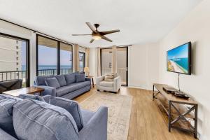 uma sala de estar com um sofá azul e uma ventoinha de tecto em Seaside Beach & Racquet 5614 em Romar Beach