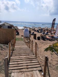 een houten loopbrug op een strand met stoelen en de oceaan bij Traditional Stone House with breathtaking view. in Zakharo