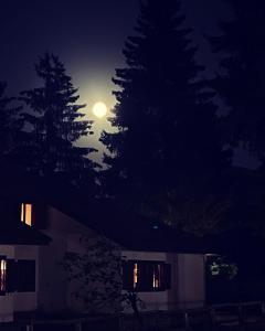 Una luna llena elevándose sobre una casa por la noche en Chalet dell'Orso, en Pescasseroli