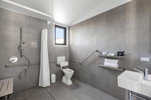 a bathroom with a shower and a toilet and a sink at Reflections Urunga - Holiday Park in Urunga