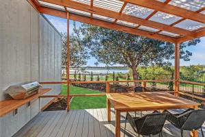 a patio with a wooden table and chairs on a deck at Reflections Urunga - Holiday Park in Urunga