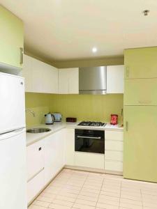 a kitchen with white cabinets and a stove top oven at SUNSET GETAWAY GLENELG in Glenelg