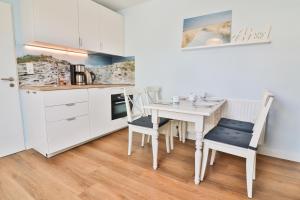 a kitchen with a white table and chairs in a room at Steuerrad in Langeoog