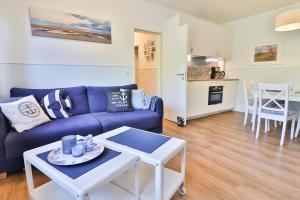 a living room with a blue couch and a table at Anker in Langeoog