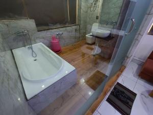 een badkamer met een wit bad en een wastafel bij HOTEL ROCK in Anand