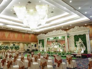 a banquet hall with white chairs and a stage at Hotel Horison Ultima Bekasi in Bekasi