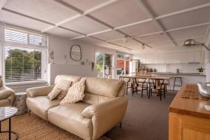 a living room with a couch and a kitchen at Elusive Penguin in Bicheno