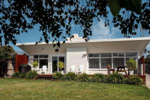 a white house with white chairs in the yard at Elusive Penguin in Bicheno