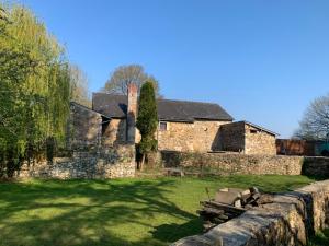 an old stone house with a stone wall in a yard at Le moulin du château in Blain