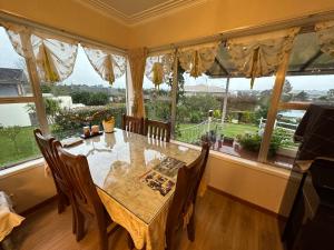 a dining room with a table and chairs and large windows at Lucky house in Auckland