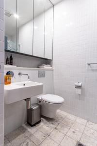a bathroom with a sink and a toilet and a mirror at Eggies Nest - Sydney City Apartment in Sydney