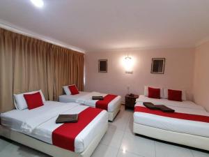 2 Betten in einem Hotelzimmer in Rot und Weiß in der Unterkunft HOTEL PANTAI VIEW in Labuan