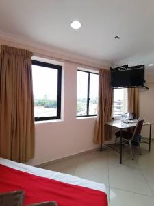 a room with a desk and a tv and two windows at HOTEL PANTAI VIEW in Labuan