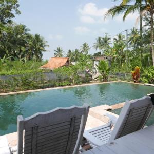 a swimming pool with two lawn chairs next to it at Pondok isoke bunggalow in Banyuwangi