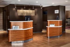 a lobby of a hotel with wooden counters at Courtyard Syracuse Carrier Circle in East Syracuse