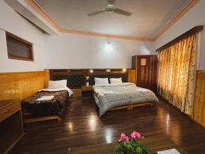 a bedroom with two beds and a couch and a fan at Hotel shaynam in Leh