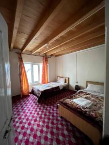 - une chambre avec 2 lits et un tapis rouge dans l'établissement Karakorum Family Guest House Hunza, à Hunza