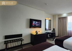 um quarto de hotel com uma cama, uma secretária e uma televisão em Hock Lee Hotel & Residences em Kuching