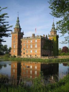 a large brick building with two towers next to a body of water at Mysigt hus i liten by nära havet in Ystad