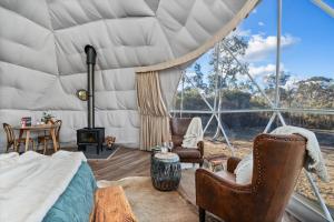Zimmer mit einem Bett und Stühlen sowie einem großen Fenster in der Unterkunft Scribbly Farm, Boutique Southern Highlands Accommodation in Joadja Creek