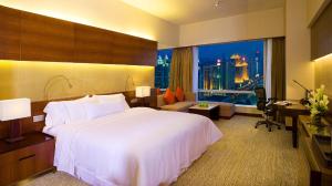 Habitación de hotel con cama blanca grande y escritorio. en The Westin Guangzhou, en Guangzhou