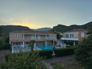 Ein Haus mit Swimmingpool und Bergen im Hintergrund in der Unterkunft Hôtel Thalassa in Saint-Florent