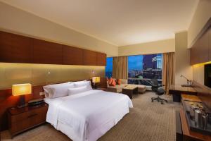 a bedroom with a large white bed and a living room at The Westin Guangzhou in Guangzhou