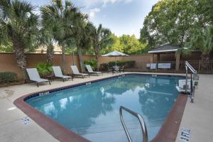 a large swimming pool with chairs and trees at Courtyard by Marriott Valdosta in Valdosta