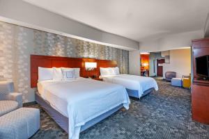 a hotel room with two beds and a flat screen tv at Courtyard by Marriott Tulsa Woodland Hills in Tulsa