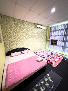 Dos camas en una habitación con sábanas rosas. en VIE HOMESTAY TAWAU, en Tawau